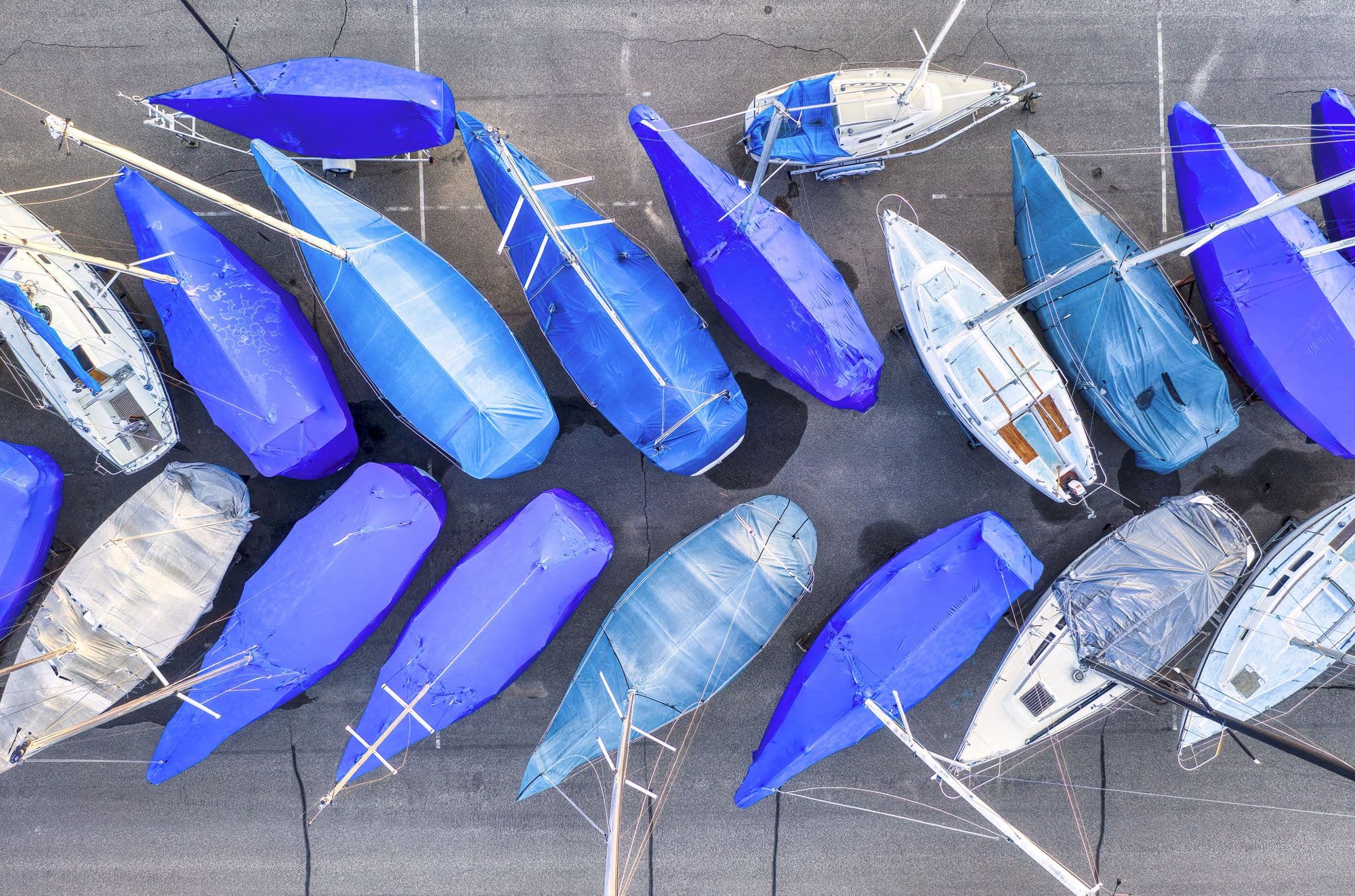 Overhead view of moored sailboats wearing fitted covers at a marina