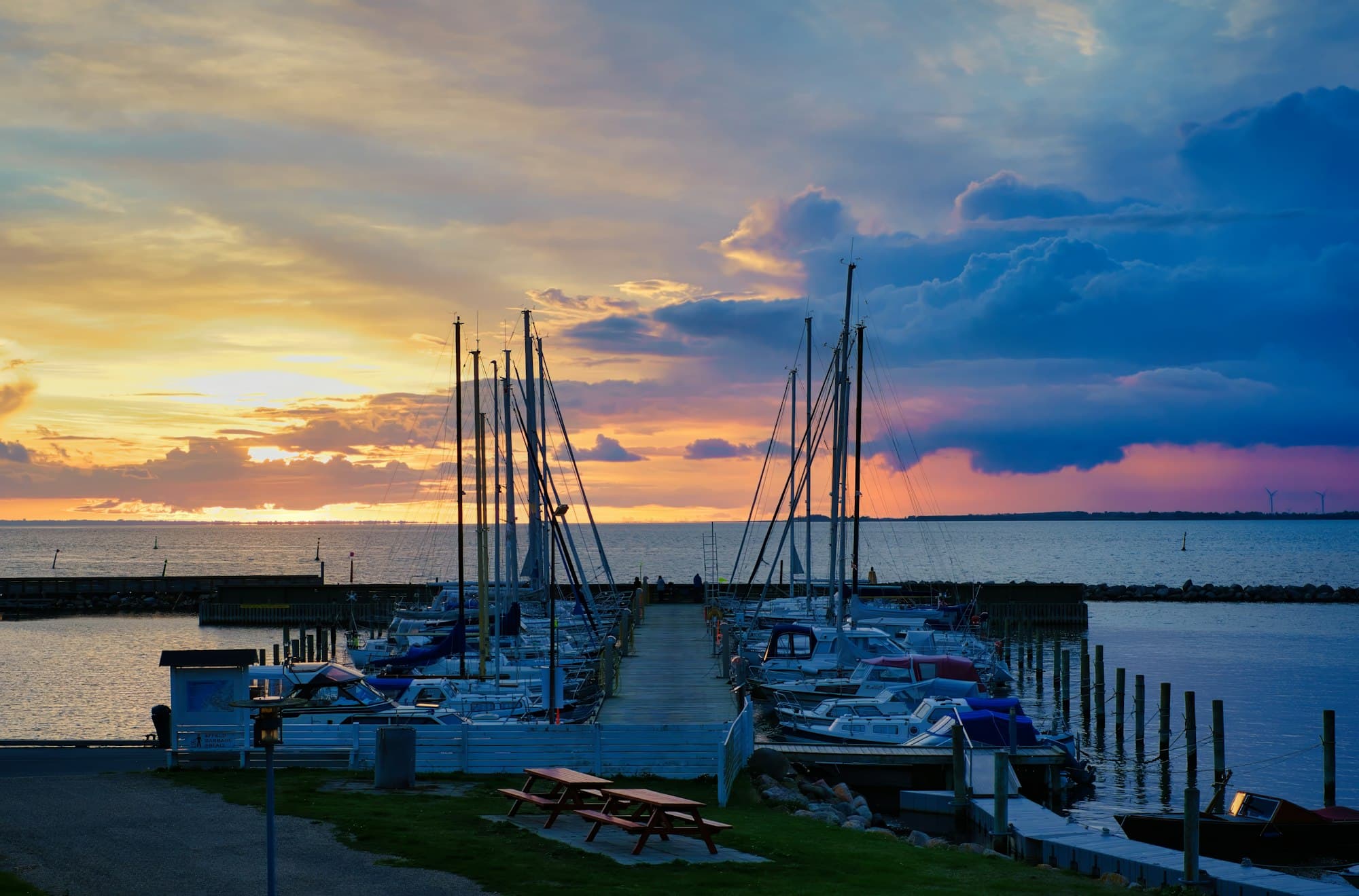 Sailboats docked at a marina under a sunset sky